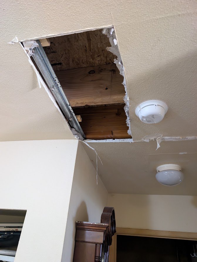 Ceiling inspection opening showing joists and subfloor after an apartment water leak near downtown Bellingham, WA